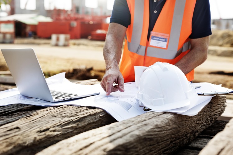 closeup-of-contractor-in-construction-site-pointing-at-plan-on-wooden-sleeper-min (2)
