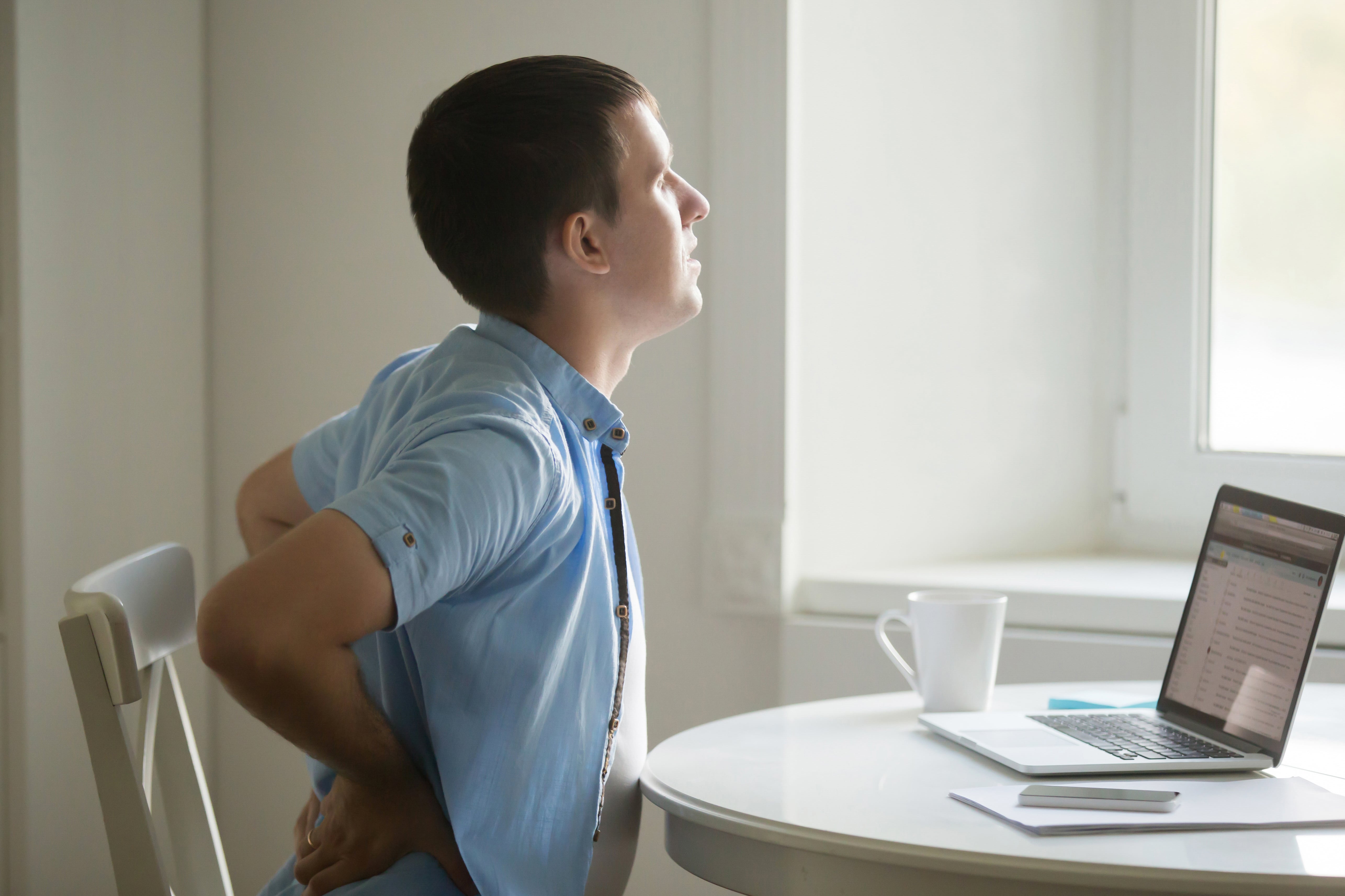 profile-portrait-of-man-at-laptop-stretching-backache-position-min