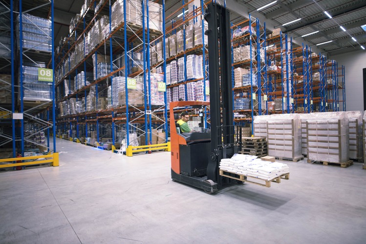 worker-operating-forklift-machine-and-relocating-goods-in-large-warehouse-center-min